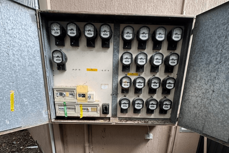 An open metering cabinet with rows of meters