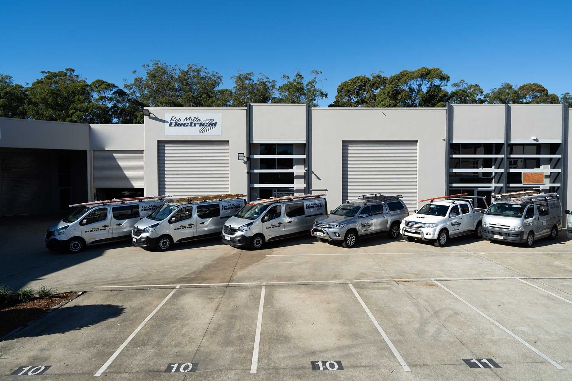 Rob Milla Electrical vans and utes lined up outside the workshop in Molendinar